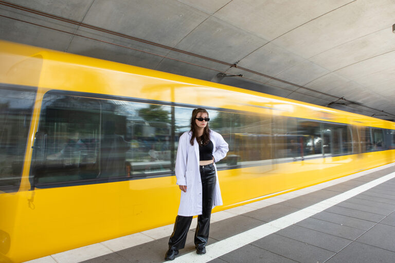 Eine junge Frau steht vor einer Stadtbahn.